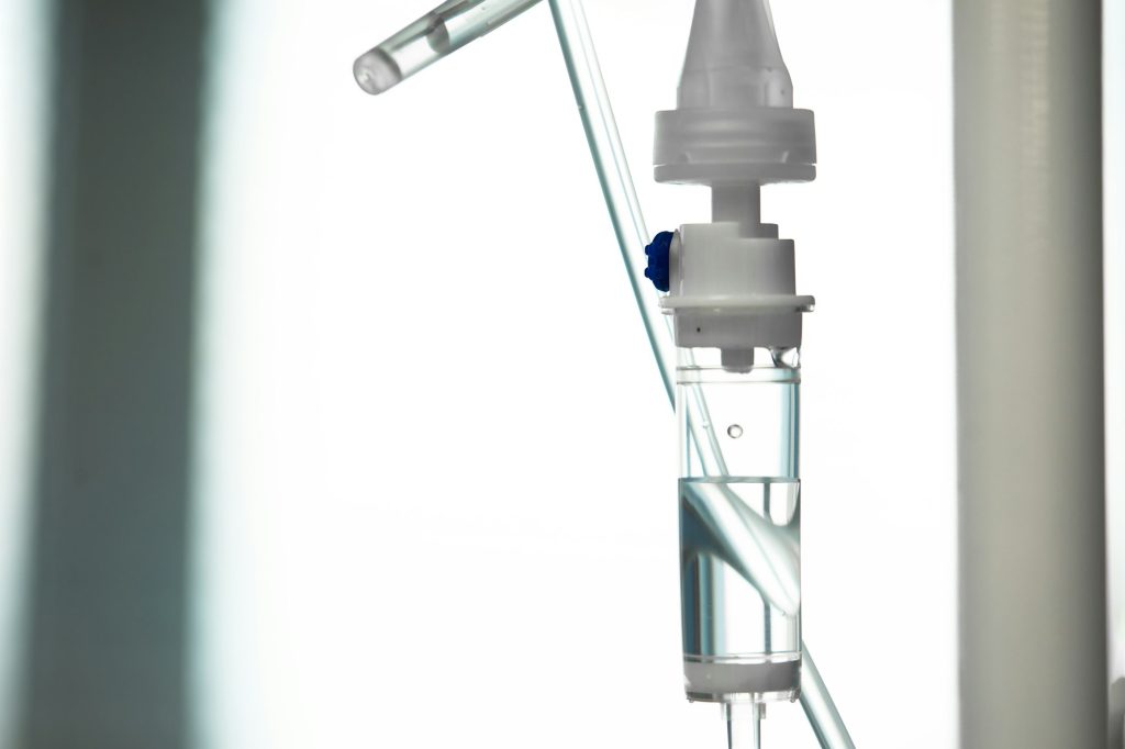 Close-up of IV tube. Action. Dropper with drug slowly dripping down tube. IV tubes for sick patient